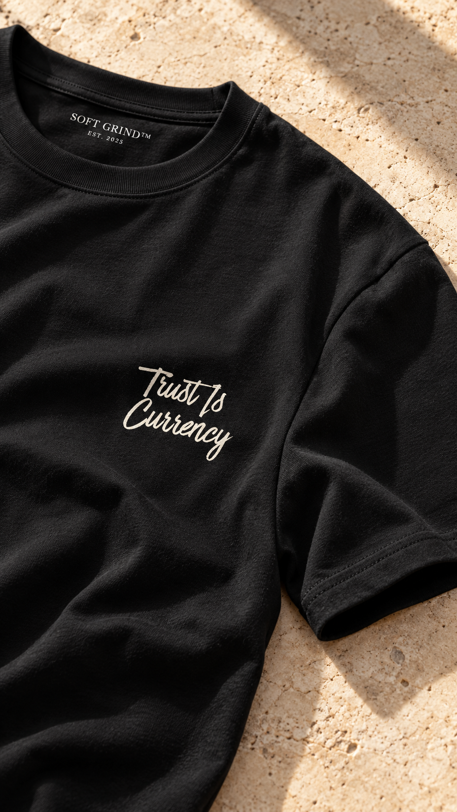 SOFT GRIND™ EST. 2025 Tee in black, worn against ivory stone